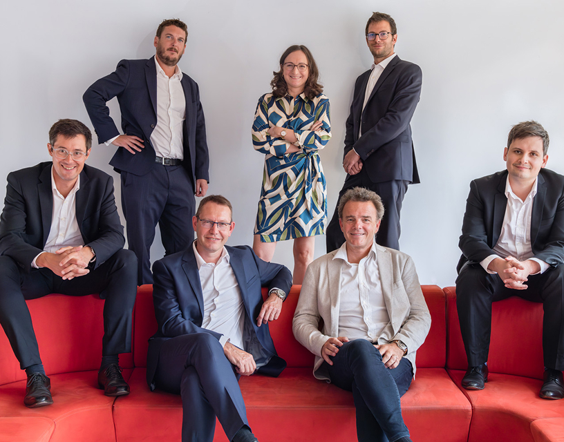 Plusieurs personnes assises sur un canapé, d'autres debout derrière